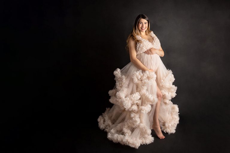 Schwangere Frau in pompösen Haute Couture Kleid bei einem Indoor Schwangerschaftsshooting