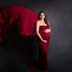Schwangere Frau mit rotem fliegenden Kleid.