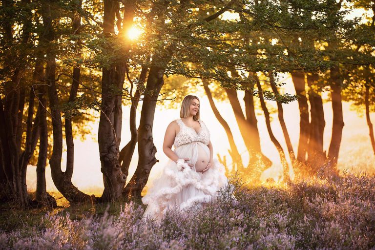 Schwangere Frau steht mit wunderschönem weißen Wolkenkleid in märchenhafter Kulisse unter einem großen Baum in der Mehlinger Heide - Sanja Balceva ist deine Babybauch-Fotografin für Mannheim, Heidelberg, Darmstadt und Umgebung