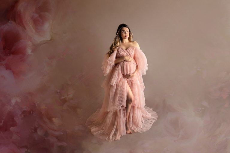 Schwangere Frau mit rosa Haute Couture Tüll Kleid vor einem blumigen Hintergrund im Fotostudio in Birkenau.
