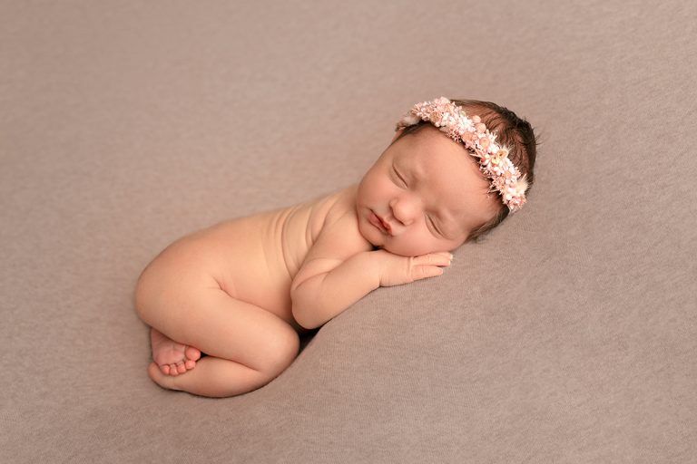 Neugeborenes Mädchen liegt gemütlich auf beigefarbenem Hintergrund – Neugeborenen-Foto entstanden beim Newborn-Shooting im Studio bei Mannheim / Heidelberg