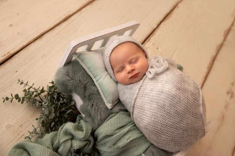 Neugeborenes Baby liegt eingepuckt auf Bettchen auf mintgrünen Tüchern und Eykalyptus – Neugeborenen-Fotoshooting in Birkenau bei Mannheim / Darmstadt