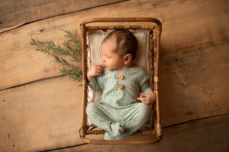 Neugeborenes Baby posiert im Mini-Schaukelstuhl für ein Neugeborenen-Fotoshooting