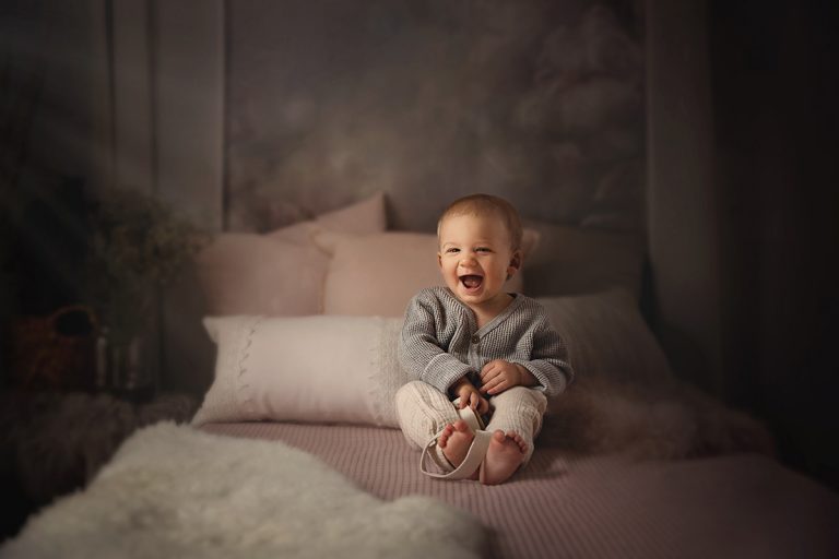 Kleiner Junge sitzt auf Bett und lacht - Sanja Balceva - deine Kinderfotografin für Mannheim, Heidelberg, Darmstadt und Umgebung