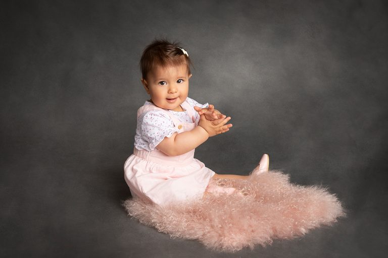 9 Monate altes Mädchen sitzt auf rosa Fell und klatscht in die Hände - Sanja Balceva - deine Fotografin für wundervolle Kinderfotos in Mannheim, Heidelberg, Darmstadt und Umgebung