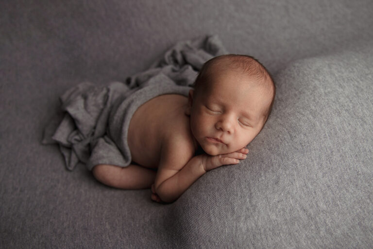 Neugeborener Baby Junge schläft auf einer grauen Decke